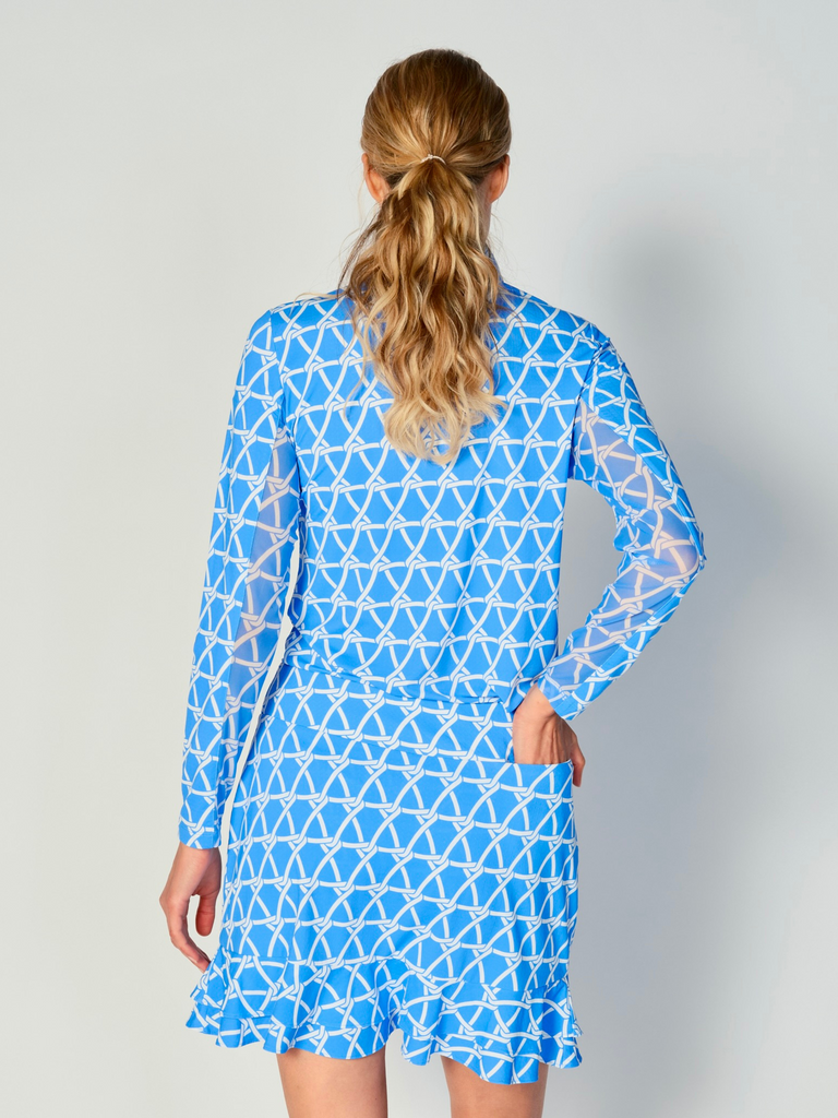 A woman is showcasing the back of the G Lifestyle Quarter Zip Sun Protection Top in Nautical Bright Peri – marine-inspired rope-knot print from Spring Summer 2024 Collection. The top is tailored with a form-fitting silhouette, complete with long sleeves and a high collar for maximum sun protection. Notably, it includes smooth mesh underarm inserts, which are seamlessly integrated for enhanced breathability, ensuring comfort during active use.