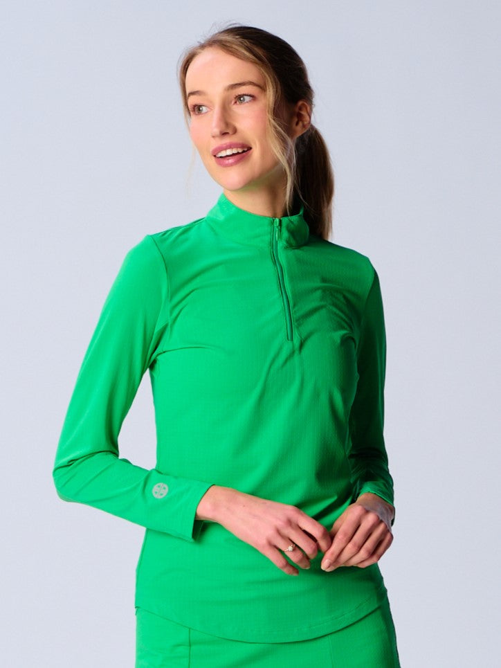A woman wears G Lifestyle Quarter Zip Sun Protection Top in Kelly Green. The top has long sleeves, an adjustable mock neck collar with a flat quarter zip, the brand’s logo discreetly placed on the right wrist. The fabric appears to have a lightweight, subtle texture, that likely offers menthol cooling, moisture wicking, breathability, sun safety and comfort. Suitable for golf, tennis, padel tennis, pickleball or even cycling.