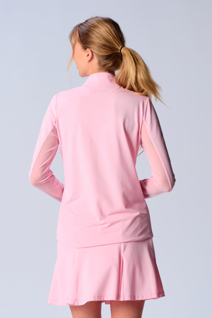 A woman is showcasing the back of the G Lifestyle Quarter Zip Sun Protection Top in Light Pink, designed with practicality and style in mind. The top is tailored with a form-fitting silhouette, complete with long sleeves and a high collar for maximum sun protection. Notably, it includes smooth mesh underarm inserts, which are seamlessly integrated for enhanced breathability, ensuring comfort during active use. 