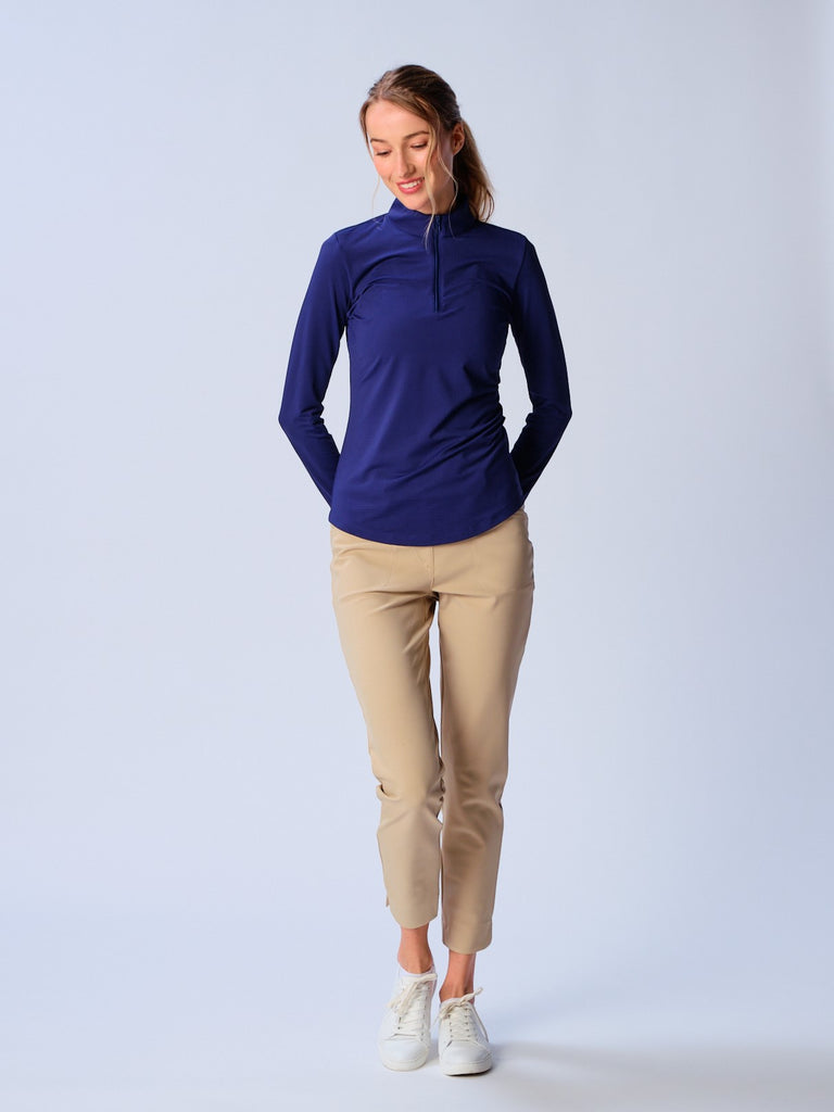 A woman wears G Lifestyle Quarter Zip Sun Protection Top in True Navy. The top has long sleeves, an adjustable mock neck collar with a flat quarter zip, the brand’s logo discreetly placed on the right wrist. The fabric appears to have a lightweight, subtle texture, that likely offers menthol cooling, moisture wicking, breathability, sun safety and comfort. Suitable for golf, tennis, padel tennis, pickleball or even cycling.