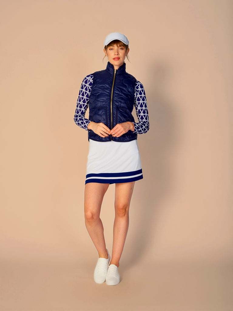 A woman models the G Lifestyle Quarter Zip Sun Protection Top in Nautical True Navy – marine-inspired rope-knot print from Spring Summer 2024 Collection. The top has long sleeves, an adjustable mock neck collar with a flat quarter zip. The fabric appears to have a lightweight, subtle texture, that likely offers menthol cooling, moisture wicking, breathability, sun safety and comfort. Suitable for golf, tennis, padel tennis, pickleball or even cycling.