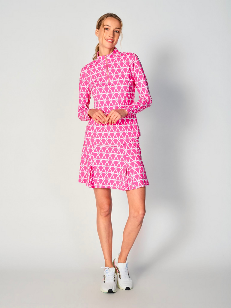 A woman models the G Lifestyle Quarter Zip Sun Protection Top in Nautical Hot Pink – marine-inspired rope-knot print from Spring Summer 2024 Collection. The top has long sleeves, an adjustable mock neck collar with a gold quarter zip, logo placed on the right wrist. The fabric appears to have a lightweight, subtle texture, that likely offers menthol cooling, moisture wicking, breathability, sun safety and comfort. Suitable for golf, tennis, padel tennis, pickleball or even cycling.