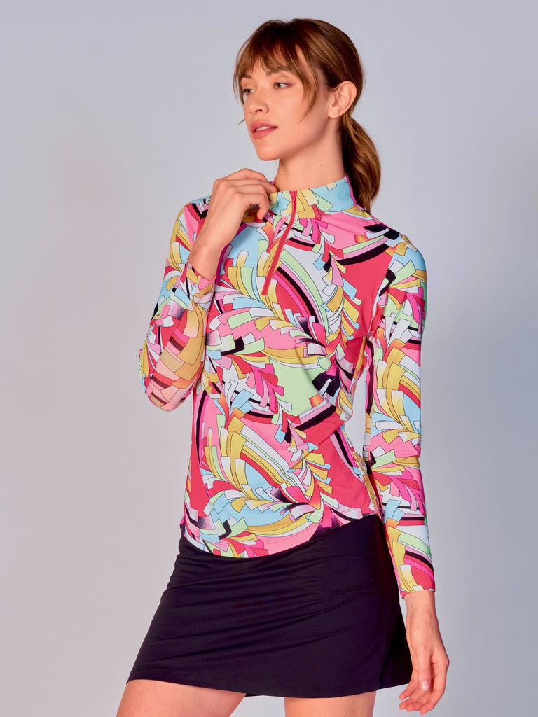A woman models the G Lifestyle Quarter Zip Sun Protection Top in St Barths Coral - abstract print of the Spring Summer 2024 Collection. The top has long sleeves, an adjustable mock neck collar with a flat quarter zip. The fabric appears to have a lightweight, subtle texture, that likely offers menthol cooling, moisture wicking, breathability, sun safety and comfort. Suitable for golf, tennis, padel tennis, pickleball or even cycling.