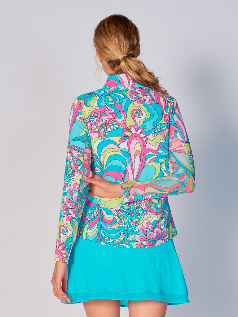 A woman is showcasing the back of the G Lifestyle Quarter Zip Sun Protection Top in Illusion -abstract print of the Spring Summer 2024 Collection. The top is tailored with a form-fitting silhouette, complete with long sleeves and a high collar for maximum sun protection. Notably, it includes smooth mesh underarm inserts, which are seamlessly integrated for enhanced breathability, ensuring comfort during active use.