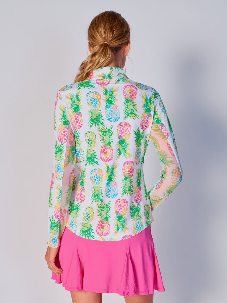 A woman is showcasing the back of the G Lifestyle Quarter Zip Sun Protection Top in Ananas Green - tropical print of the Spring Summer 2024 Collection. The top is tailored with a form-fitting silhouette, complete with long sleeves and a high collar for maximum sun protection. Notably, it includes smooth mesh underarm inserts, which are seamlessly integrated for enhanced breathability, ensuring comfort during active use. 