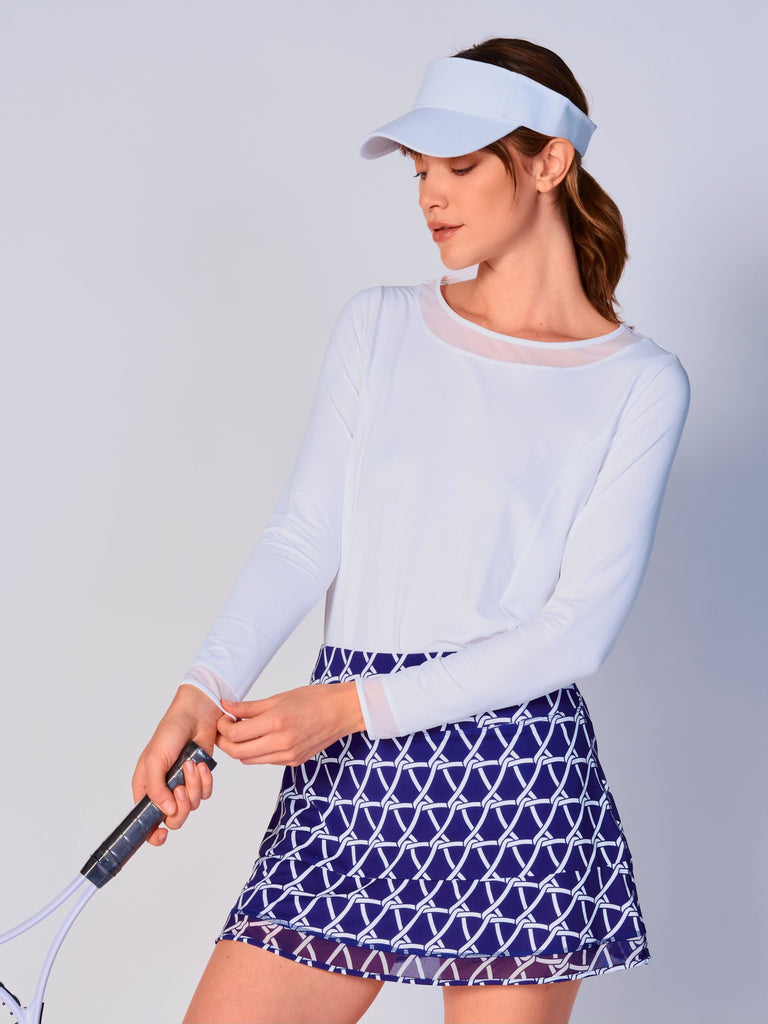 A woman wears G Lifestyle Mesh Block Long Sleeve Top in White. The top is designed with long sleeves, mesh underarm inserts for breathability, and features a round neckline with texture mesh block detailing around it and sleeve hems. The fabric appears to be lightweight, movement-friendly, with subtle texture. Suitable for various outdoor athletic activities such as golf, tennis, padel tennis, pickleball or even cycling.
