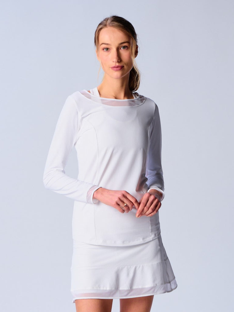 A woman wears G Lifestyle Mesh Block Long Sleeve Top in White. The top is designed with long sleeves, mesh underarm inserts for breathability, and features a round neckline with texture mesh block detailing around it and sleeve hems. The fabric appears to be lightweight, movement-friendly, with subtle texture. Suitable for various outdoor athletic activities such as golf, tennis, padel tennis, pickleball or even cycling.
