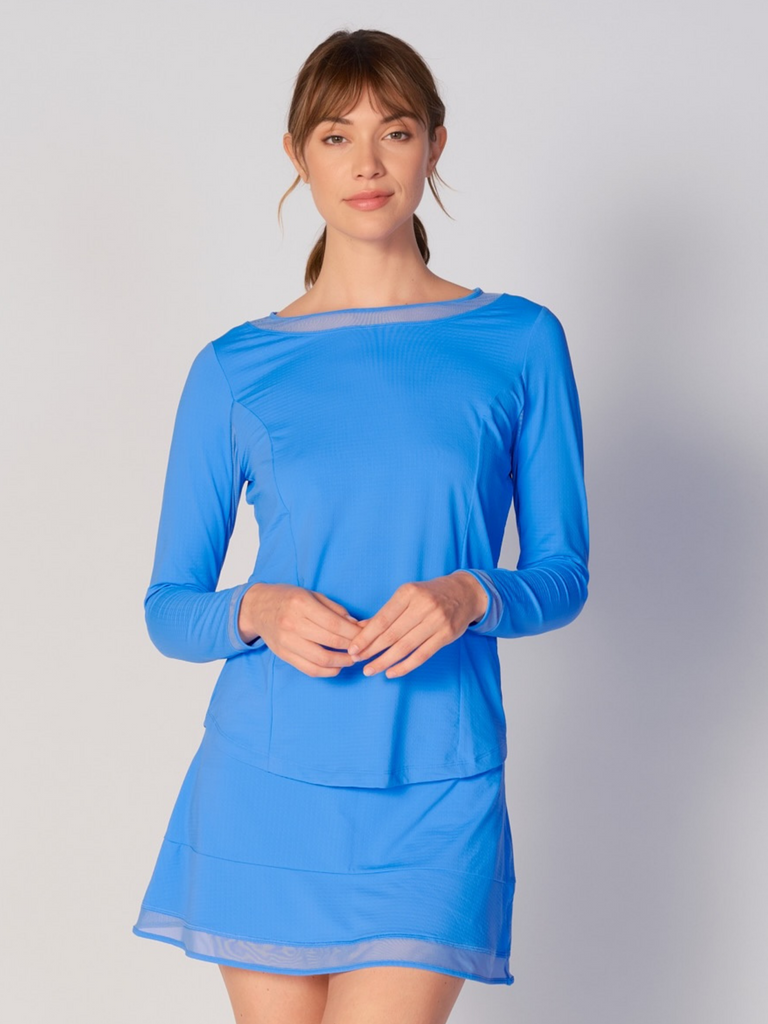 A woman wears G Lifestyle Mesh Block Long Sleeve Top in Bright Peri. The top is designed with long sleeves, mesh underarm inserts for breathability, and features a round neckline with texture mesh block detailing around it and sleeve hems. The fabric appears to be lightweight, movement-friendly, with subtle texture. Suitable for various outdoor athletic activities such as golf, tennis, padel tennis, pickleball or even cycling.