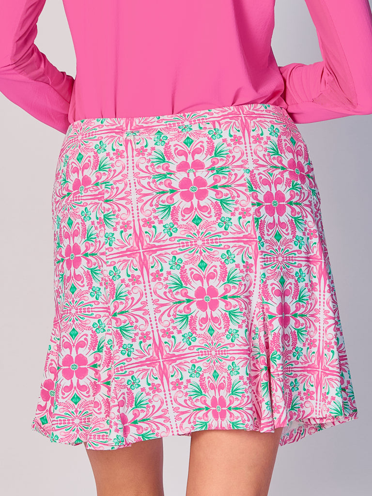 The close-up image showcases the back view of the G Lifestyle Flare Godet Skort in Pink Tile – symmetrical ornamental print of the Spring Summer 2024 Collection. The skort waistband is flat and wide with a single horizontal utility pocket with zip closure. The subtle texture of the soft stretchy fabric is noticeable. The stitching is meticulous, ensuring a durable and comfortable fit. This skort is suitable for tennis, pickleball, padel tennis, golf. 