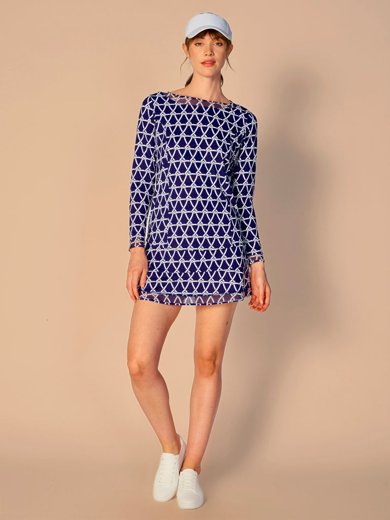 A woman wears G Lifestyle Mesh Block Long Sleeve Top in Nautical True Navy – marine-inspired rope-knot print from Spring Summer 2024 Collection. The top is designed with long sleeves, mesh underarm inserts for breathability, and features a round neckline with texture mesh block detailing around it and sleeve hems. The fabric appears to be lightweight, movement-friendly, with subtle texture. Suitable for various outdoor athletic activities such as golf, tennis, padel tennis, pickleball or even cycling.
