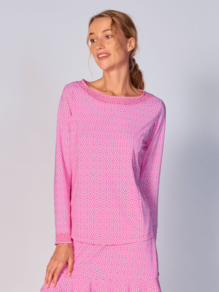 A woman wears G Lifestyle Mesh Block Long Sleeve Top in Cubic Hot Pink - geometric print of the Spring Summer 2024 Collection. The top is designed with long sleeves, mesh underarm inserts for breathability, and features a round neckline with texture mesh block detailing around it and sleeve hems. The fabric appears to be lightweight, movement-friendly, with subtle texture. Suitable for various outdoor athletic activities such as golf, tennis, padel tennis, pickleball or even cycling.