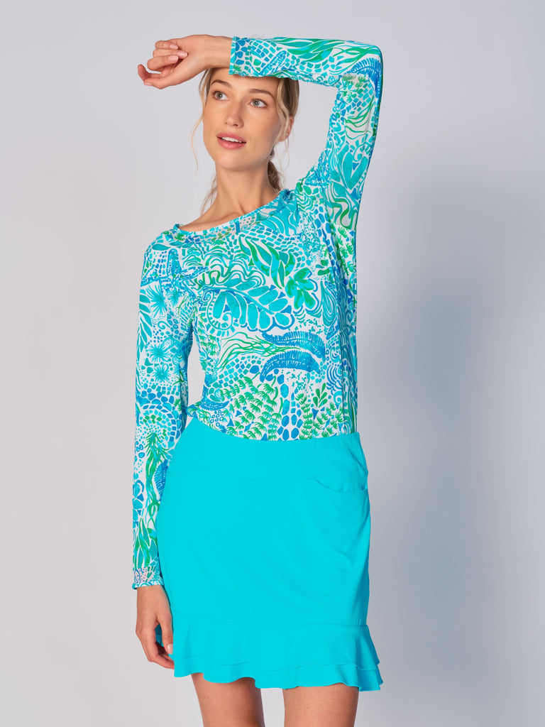 A woman wears G Lifestyle Mesh Block Long Sleeve Top in Starfish Bright Peri – sea-theme print of the Spring Summer 2024 Collection. The top is designed with long sleeves, mesh underarm inserts for breathability, and features a round neckline with texture mesh block detailing around it and sleeve hems. The fabric appears to be lightweight, movement-friendly, with subtle texture. Suitable for various outdoor athletic activities such as golf, tennis, padel tennis, pickleball or even cycling.