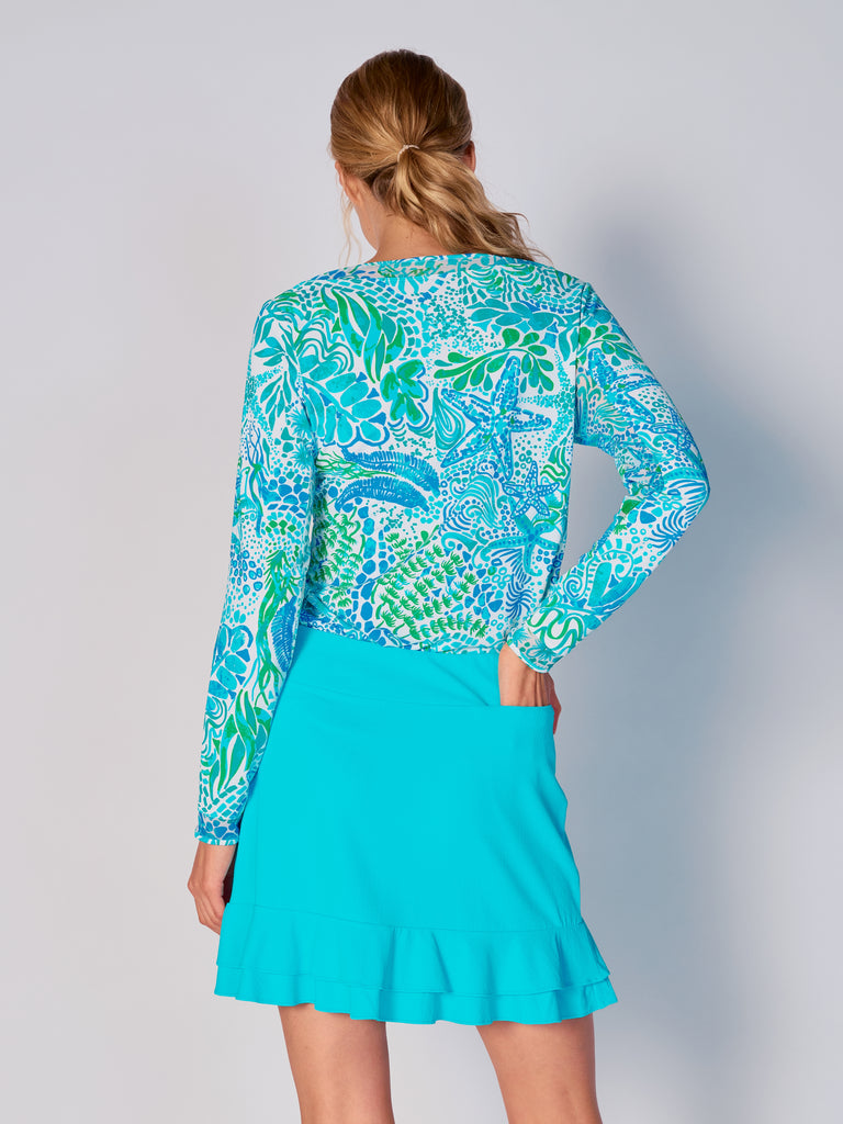 A woman is showcasing the back of the G Lifestyle Mesh Block Long Sleeve Top in Starfish Bright Peri – sea-theme print of the Spring Summer 2024 Collection. The top is tailored with a snug fit silhouette, complete with long sleeves and round neckline with mesh details. Notably, it includes smooth mesh underarm inserts, which are seamlessly integrated for enhanced breathability, ensuring comfort during active use. 