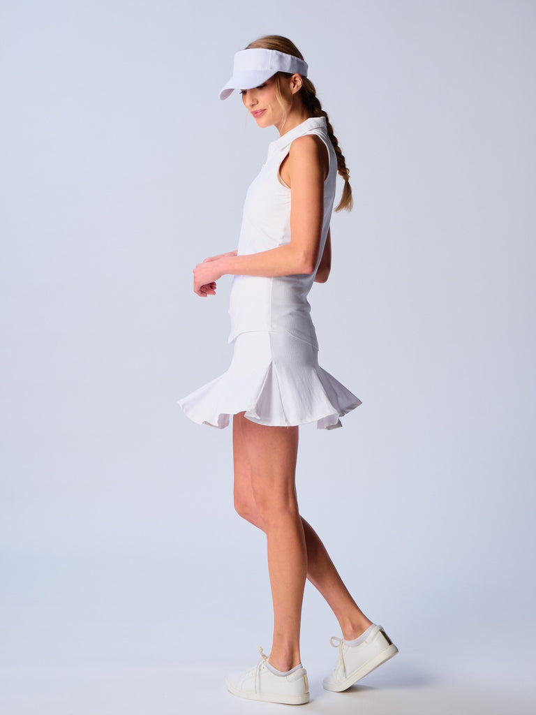 A woman pictured while twirling, showcasing the G Lifestyle Flare Godet Skort in White. This feminine and sporty skort features a fitted waistband and a flared hem with godet inserts, giving the garment playful and flirty silhouette. The length of the skort appears to be mid-thigh. The fabric looks soft, comfortable, and stretchy. This skort is suitable for tennis, pickleball, padel tennis, golf.